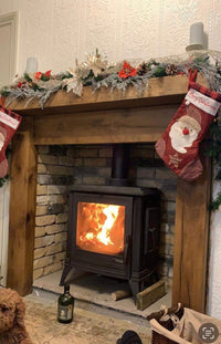 Wooden fireplace with a lit fire, surrounded by decorative items and a painting on the wall.